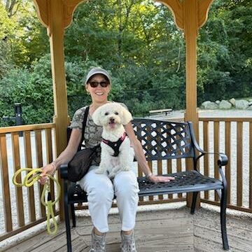 Volunteer woman with cute dog on her lap, sitting on a covered porch